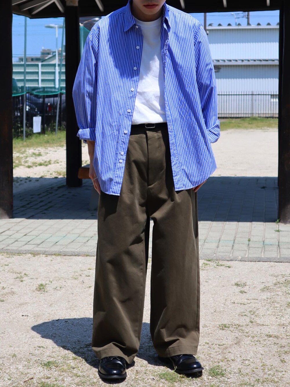 ブルー系のシャツ/ブラウス、ホワイト系のTシャツ/カットソー、グリーン系のチノパンツを着用したメンズの春コーディネートの2枚目の写真