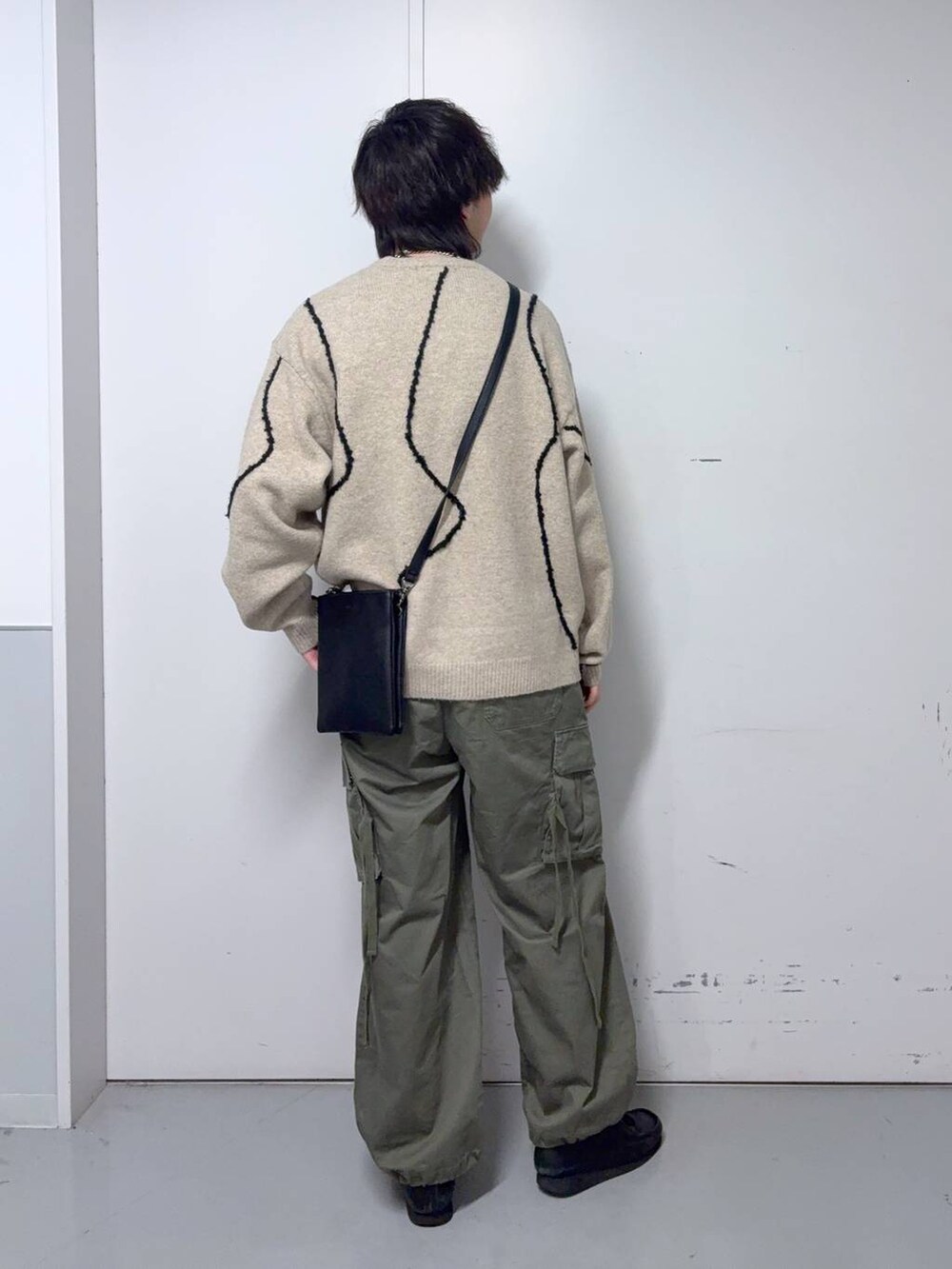 グリーン系のカーゴパンツ、ベージュ系のニット/セーター、ブラック系のショルダーバッグを着用したメンズの秋コーディネートの3枚目の写真