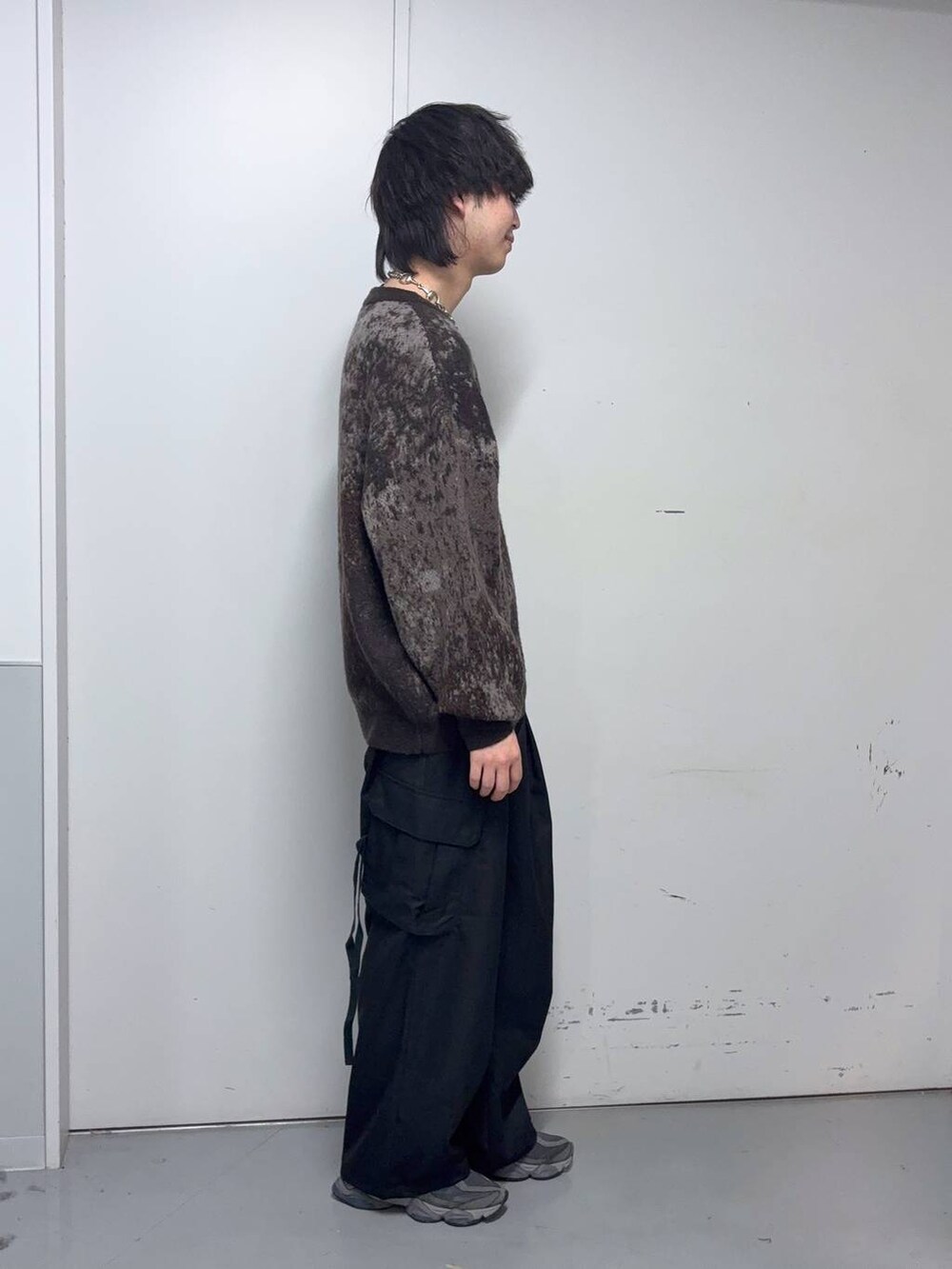 ブラウン系のニット/セーター、ブラック系のスラックス、ブルー系のソックス/靴下を着用したメンズの冬コーディネートの4枚目の写真