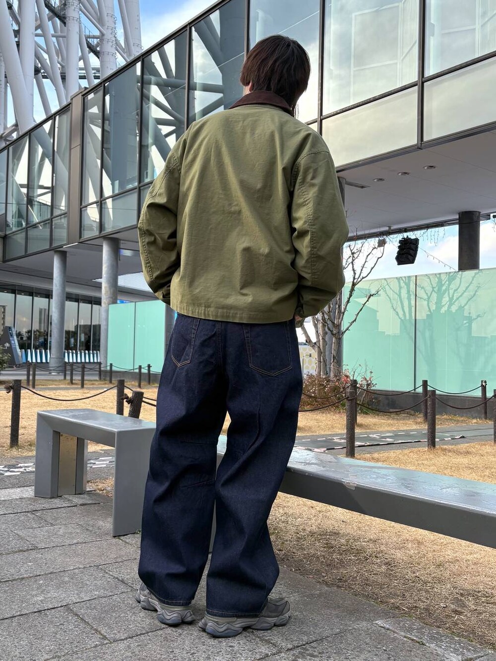 グリーン系のブルゾン、ブルー系のデニムパンツ、ブラック系のスウェットを着用したメンズの冬コーディネートの3枚目の写真