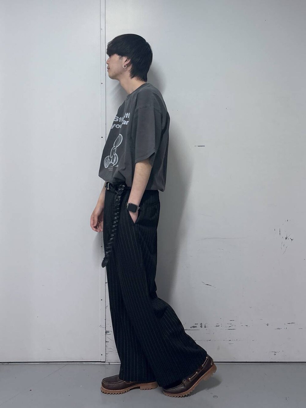 ブラック系のスラックス、グレー系のTシャツ/カットソー、ブラック系のベルトを着用したメンズの春コーディネートの2枚目の写真