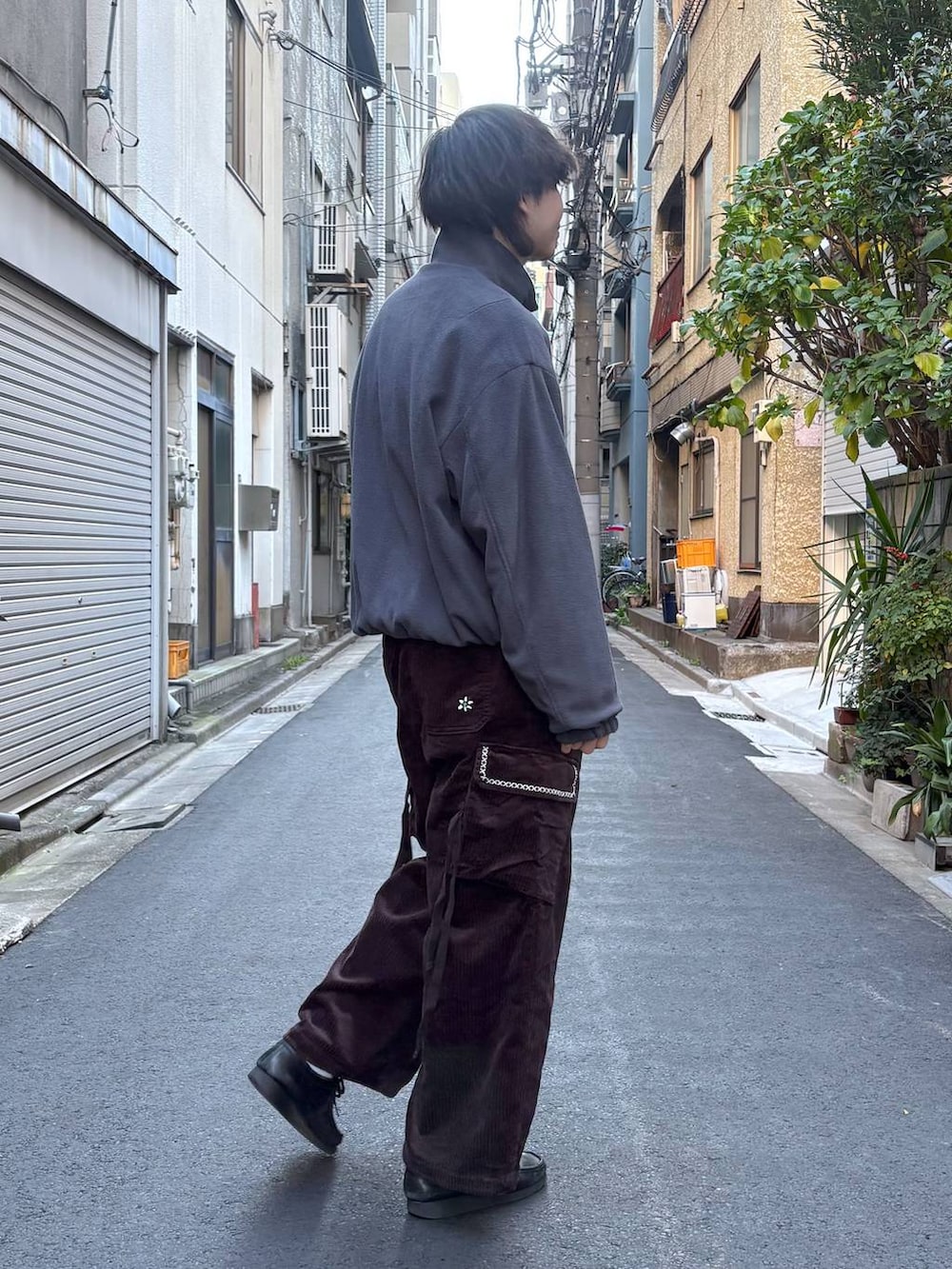 グレー系のブルゾン、ブラック系のニット/セーター、ブラウン系のカーゴパンツを着用したメンズの冬コーディネートの3枚目の写真