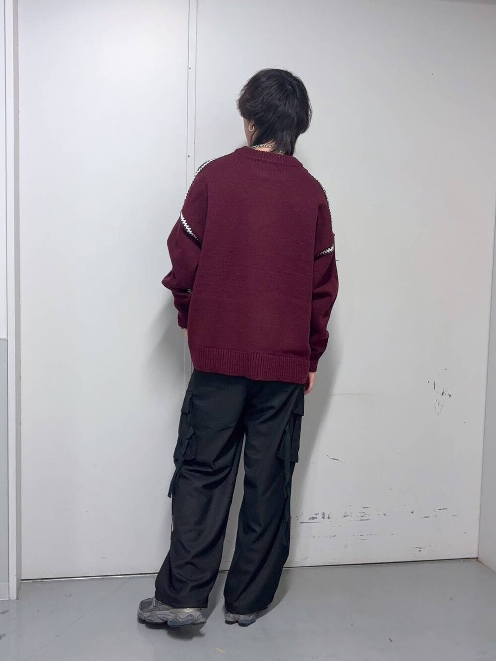 レッド系のニット/セーター、ブラック系のスラックス、ブルー系のソックス/靴下を着用したメンズの冬コーディネートの3枚目の写真