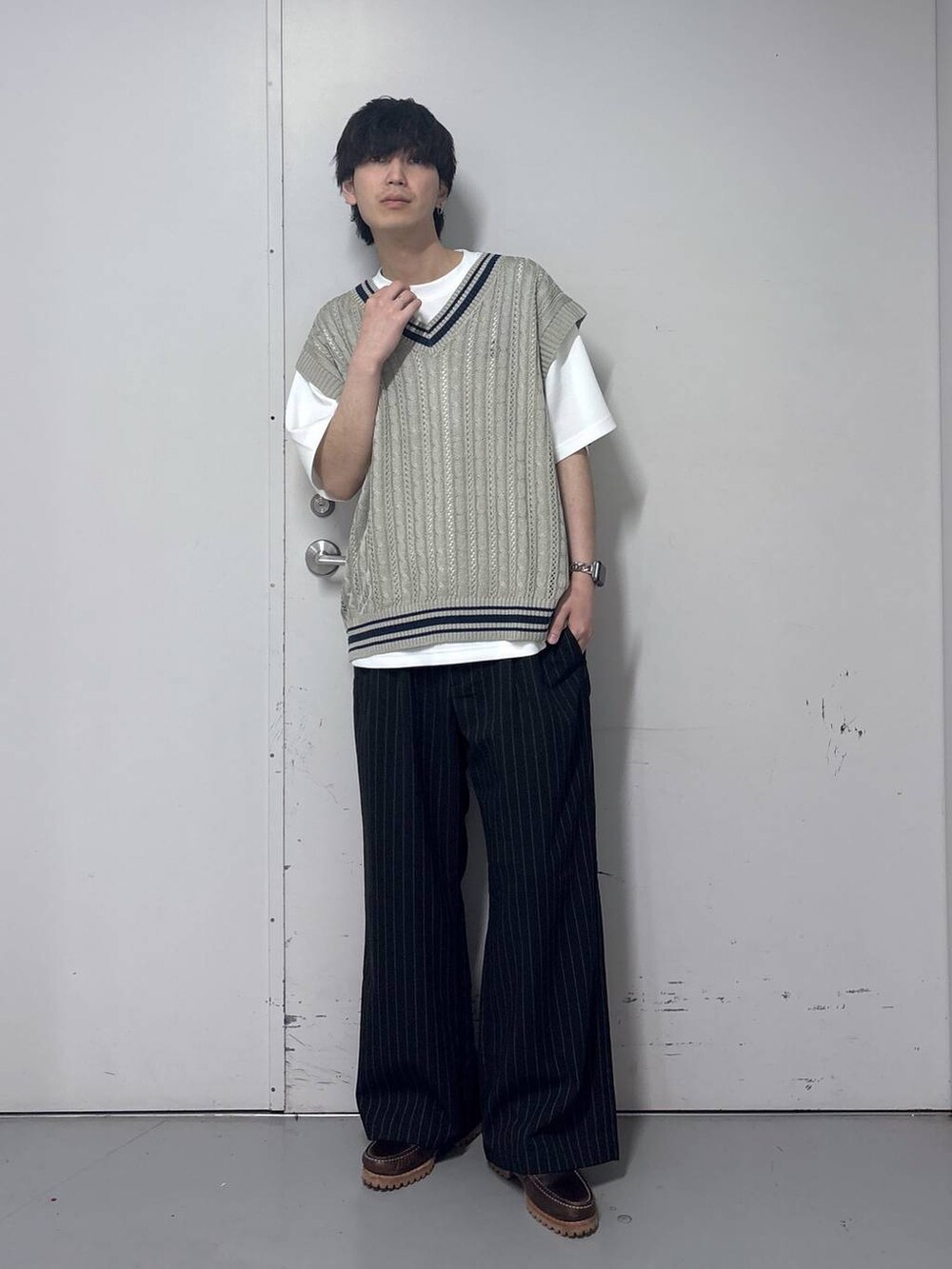 ブラック系のスラックス、ホワイト系のTシャツ/カットソー、ベージュ系のベストを着用したメンズの春コーディネートの4枚目の写真