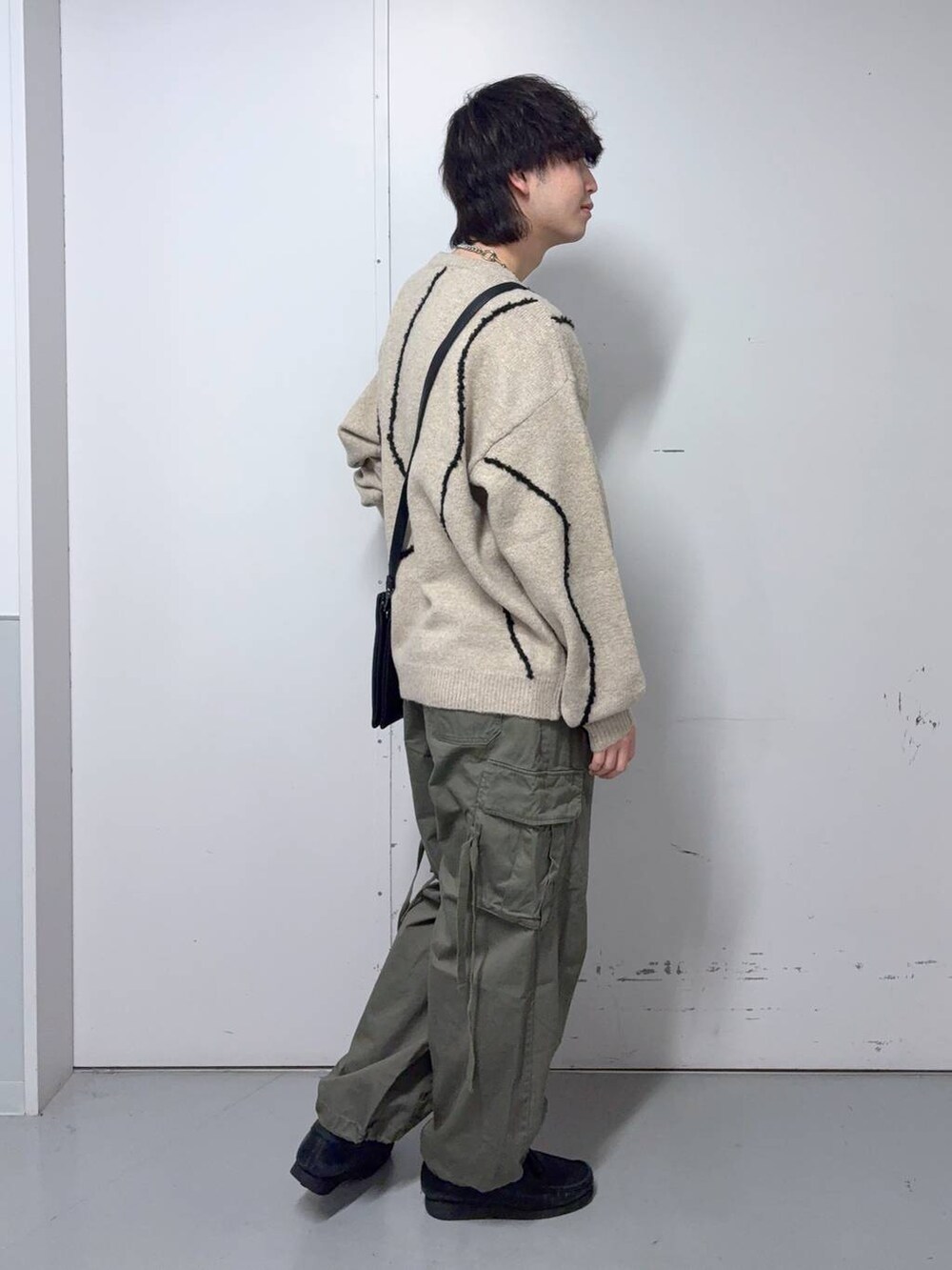 グリーン系のカーゴパンツ、ベージュ系のニット/セーター、ブラック系のショルダーバッグを着用したメンズの秋コーディネートの4枚目の写真