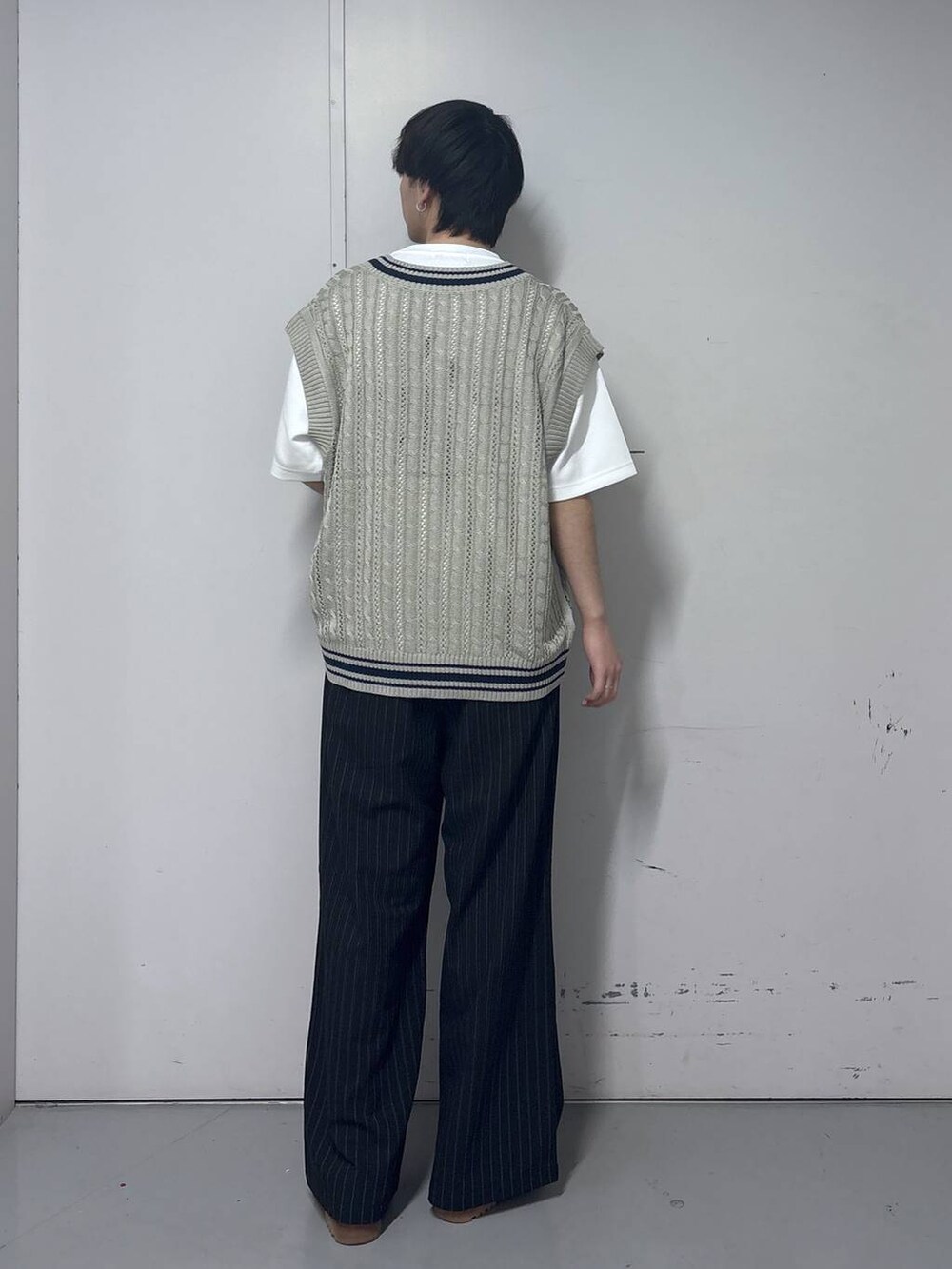 ブラック系のスラックス、ホワイト系のTシャツ/カットソー、ベージュ系のベストを着用したメンズの春コーディネートの3枚目の写真