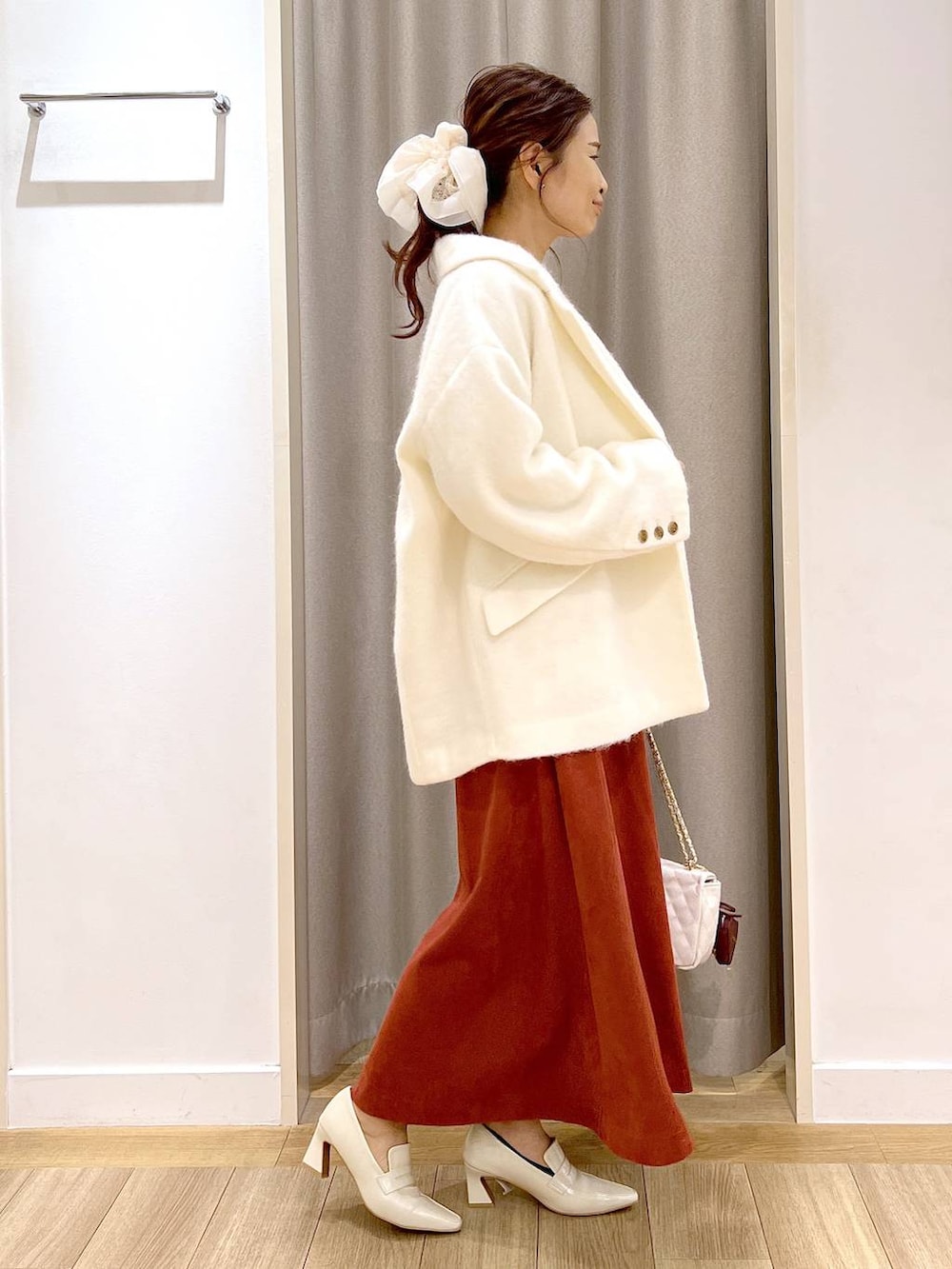 ホワイト系のピーコート、ベージュ系のローファー、レッド系のスカートを着用したレディースの秋コーディネートの5枚目の写真
