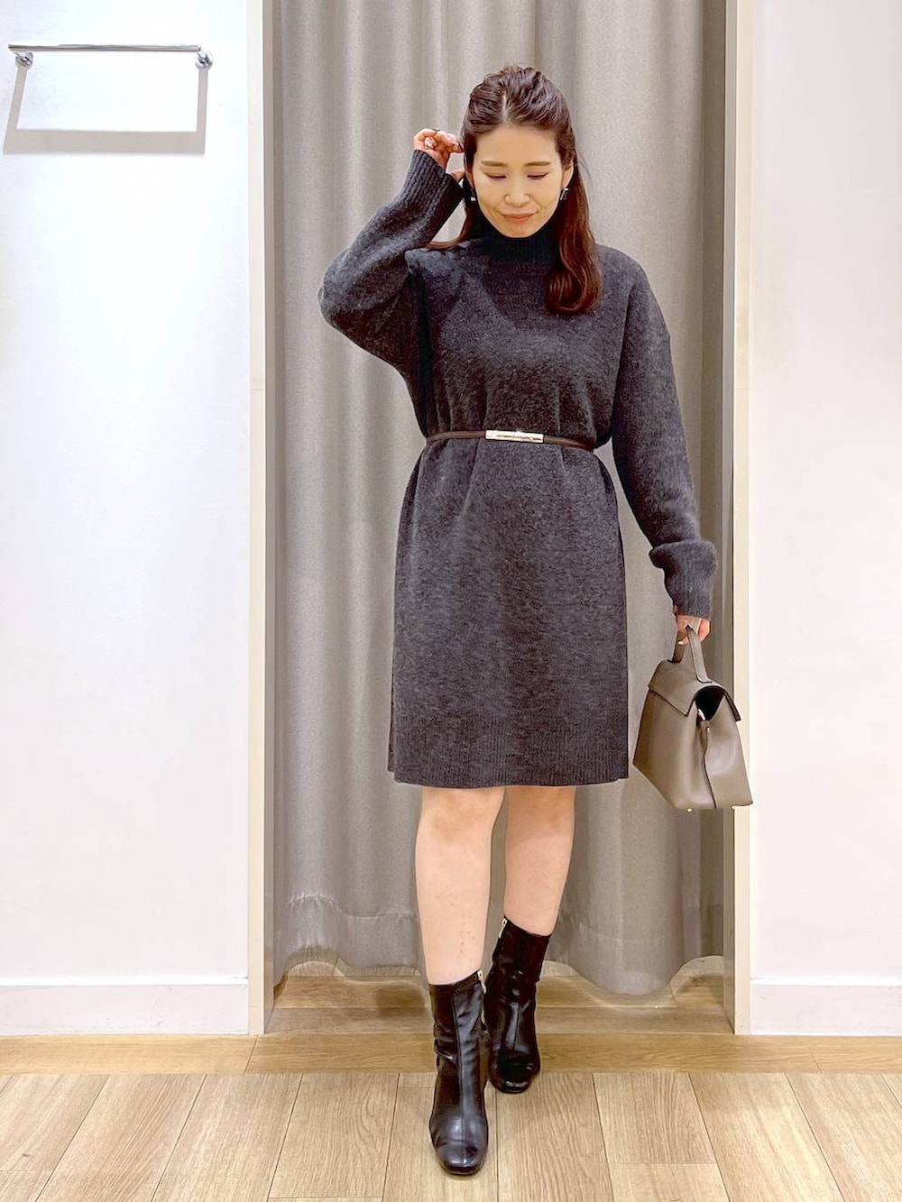 グレー系のチュニック、ブラック系のブーツ、ベージュ系のハンドバッグを着用したレディースの冬コーディネートの5枚目の写真