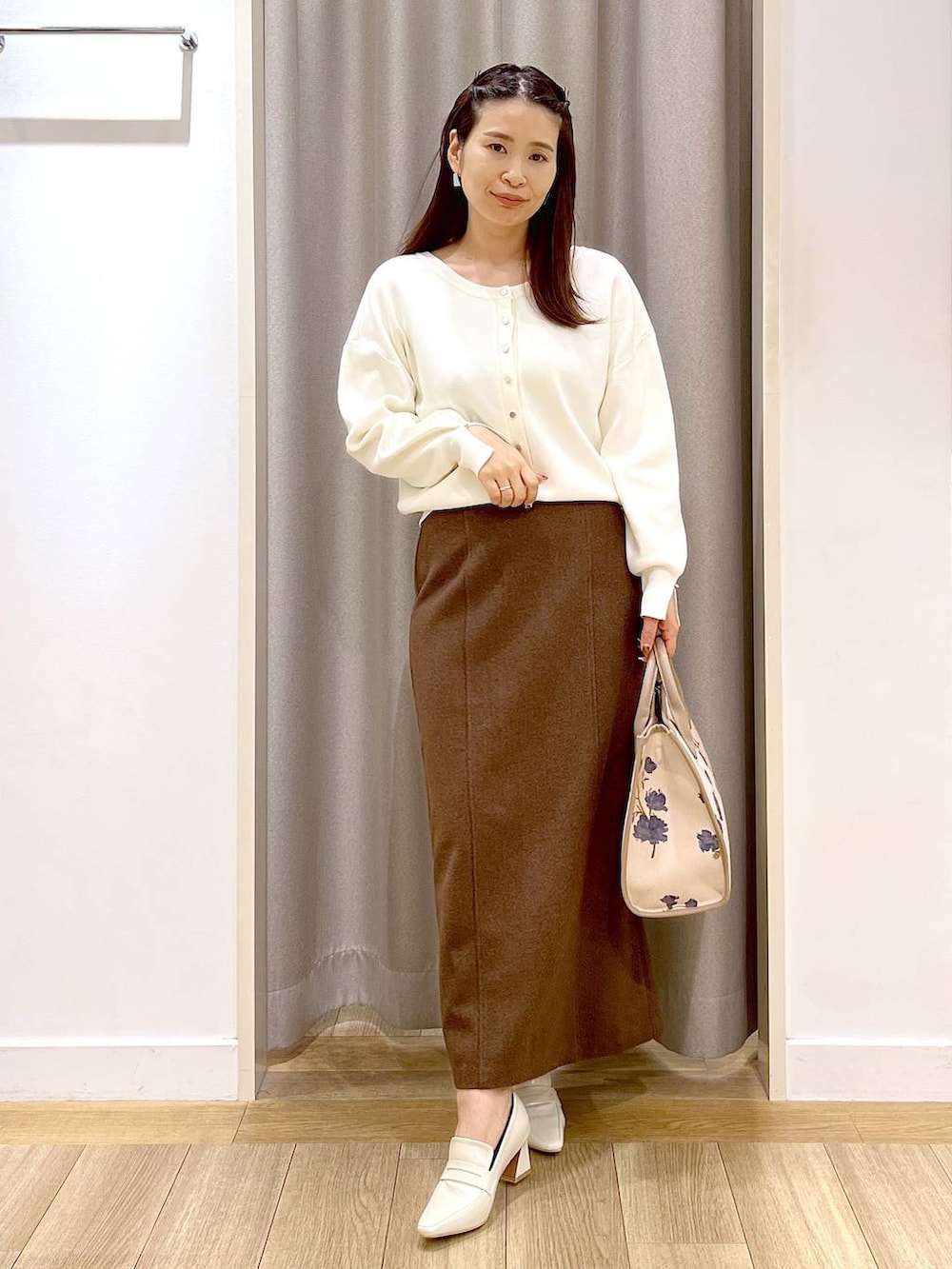ベージュ系のローファー、ホワイト系のカーディガン/ボレロ、ブラウン系のスカートを着用したレディースの秋コーディネートの2枚目の写真