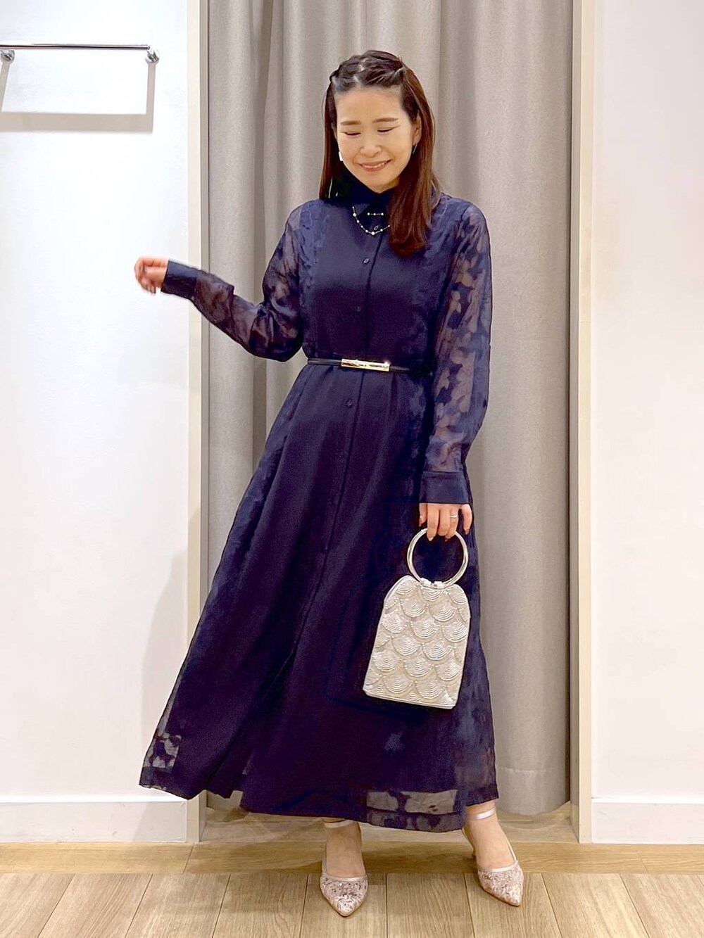 グレー系のショルダーバッグ、ベージュ系のパンプス、ブルー系のワンピースを着用したレディースの秋コーディネートの3枚目の写真