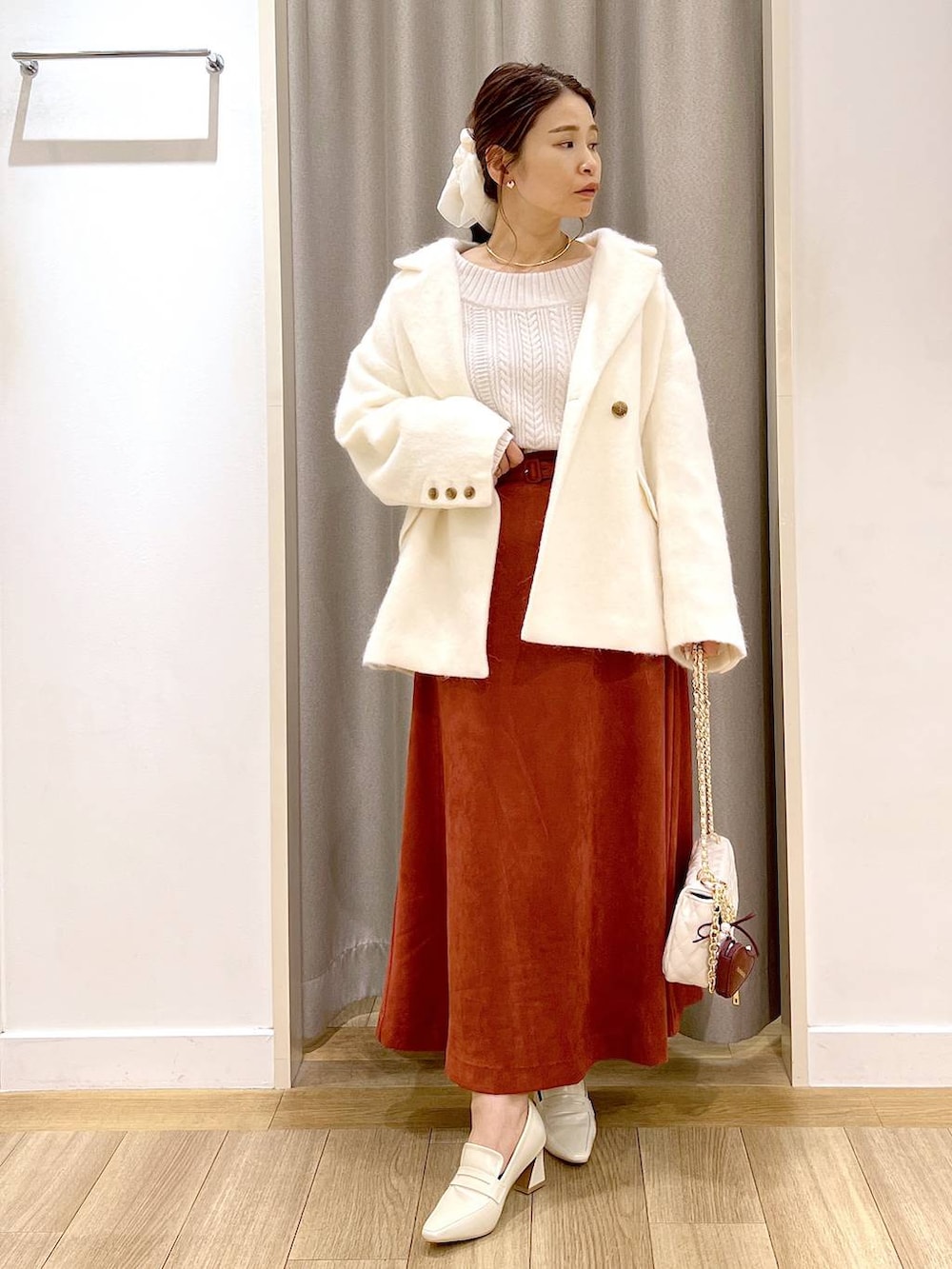ホワイト系のピーコート、ベージュ系のローファー、レッド系のスカートを着用したレディースの秋コーディネートの3枚目の写真