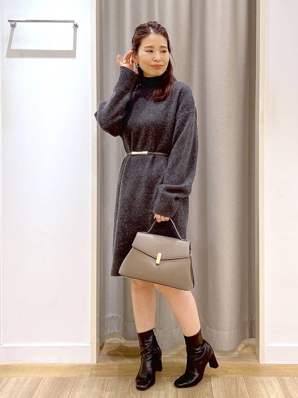 グレー系のチュニック、ブラック系のブーツ、ベージュ系のハンドバッグを着用したレディースの冬コーディネートの4枚目の写真