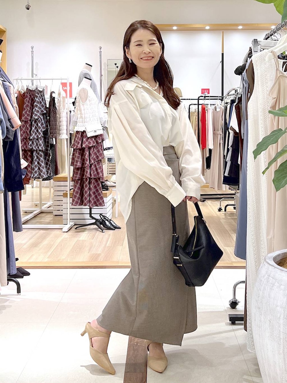 ベージュ系のスカート、ベージュ系のパンプス、ホワイト系のシャツ/ブラウスを着用したレディースの夏コーディネートの3枚目の写真