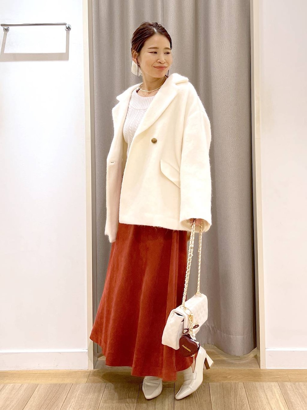 ホワイト系のピーコート、ベージュ系のローファー、レッド系のスカートを着用したレディースの秋コーディネートの2枚目の写真