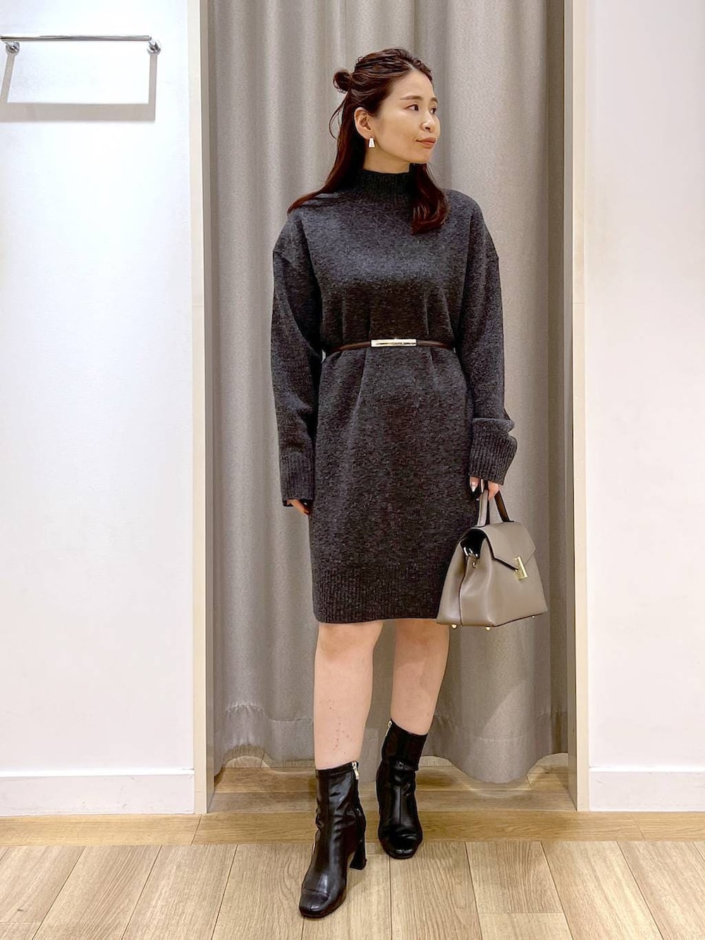 グレー系のチュニック、ブラック系のブーツ、ベージュ系のハンドバッグを着用したレディースの冬コーディネートの7枚目の写真
