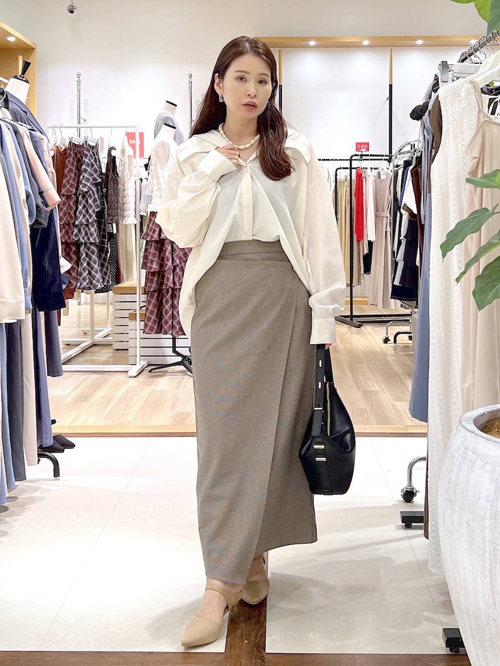 ベージュ系のスカート、ベージュ系のパンプス、ホワイト系のシャツ/ブラウスを着用したレディースの夏コーディネートの6枚目の写真