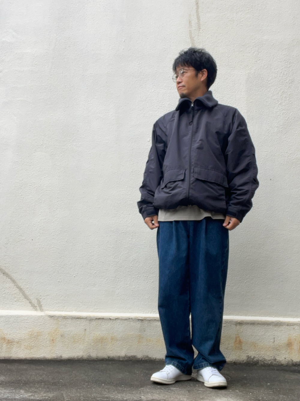 ブラウン系のTシャツ/カットソー、ブラック系のブルゾン、ブルー系のデニムパンツを着用したメンズの秋コーディネートの3枚目の写真