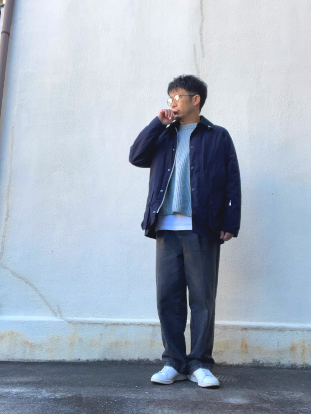 ブルー系のニット/セーター、グレー系のデニムパンツ、ホワイト系のスニーカーを着用したメンズの春コーディネートの2枚目の写真