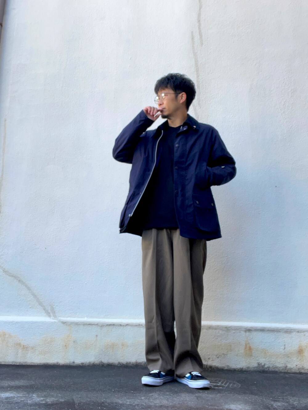 ブラウン系のスラックス、ブラック系のスウェット、ブルー系のスニーカーを着用したメンズの春コーディネートの3枚目の写真