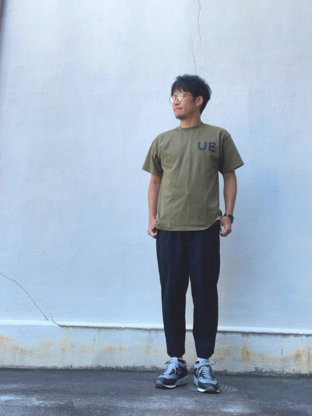 グリーン系のTシャツ/カットソー、ブラック系のスラックス、グレー系のスニーカーを着用したメンズの夏コーディネートの2枚目の写真