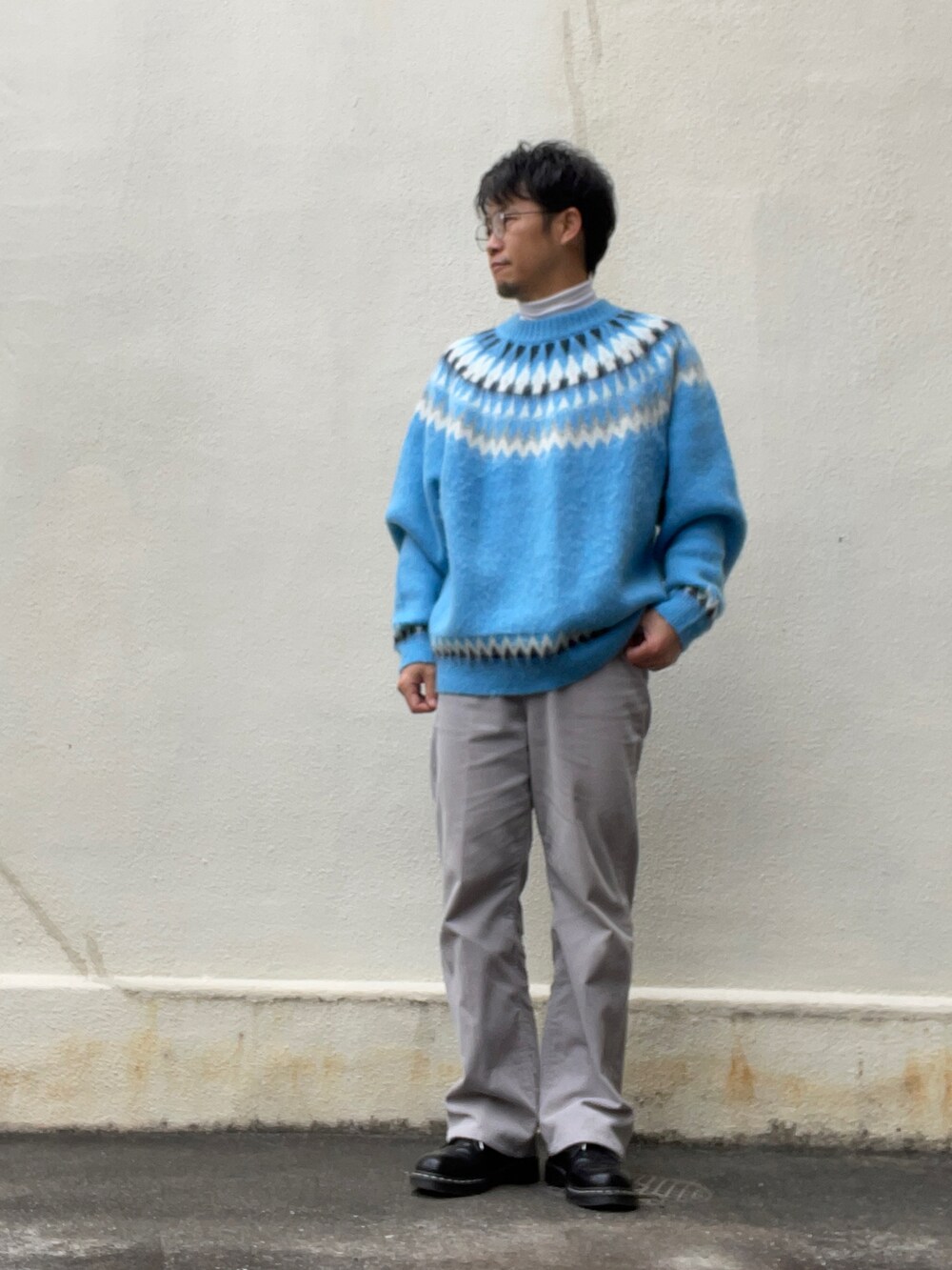 ブルー系のニット/セーター、ベージュ系のダウンジャケット/コート、グレー系のスラックスを着用したメンズの冬コーディネートの2枚目の写真