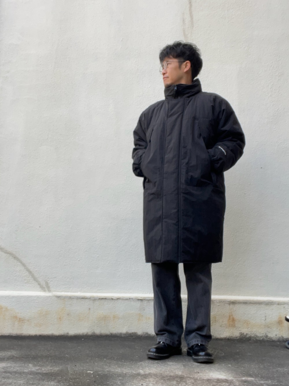 ブラック系のその他アウター、ベージュ系のニット/セーター、グレー系のデニムパンツを着用したメンズの春コーディネートの2枚目の写真