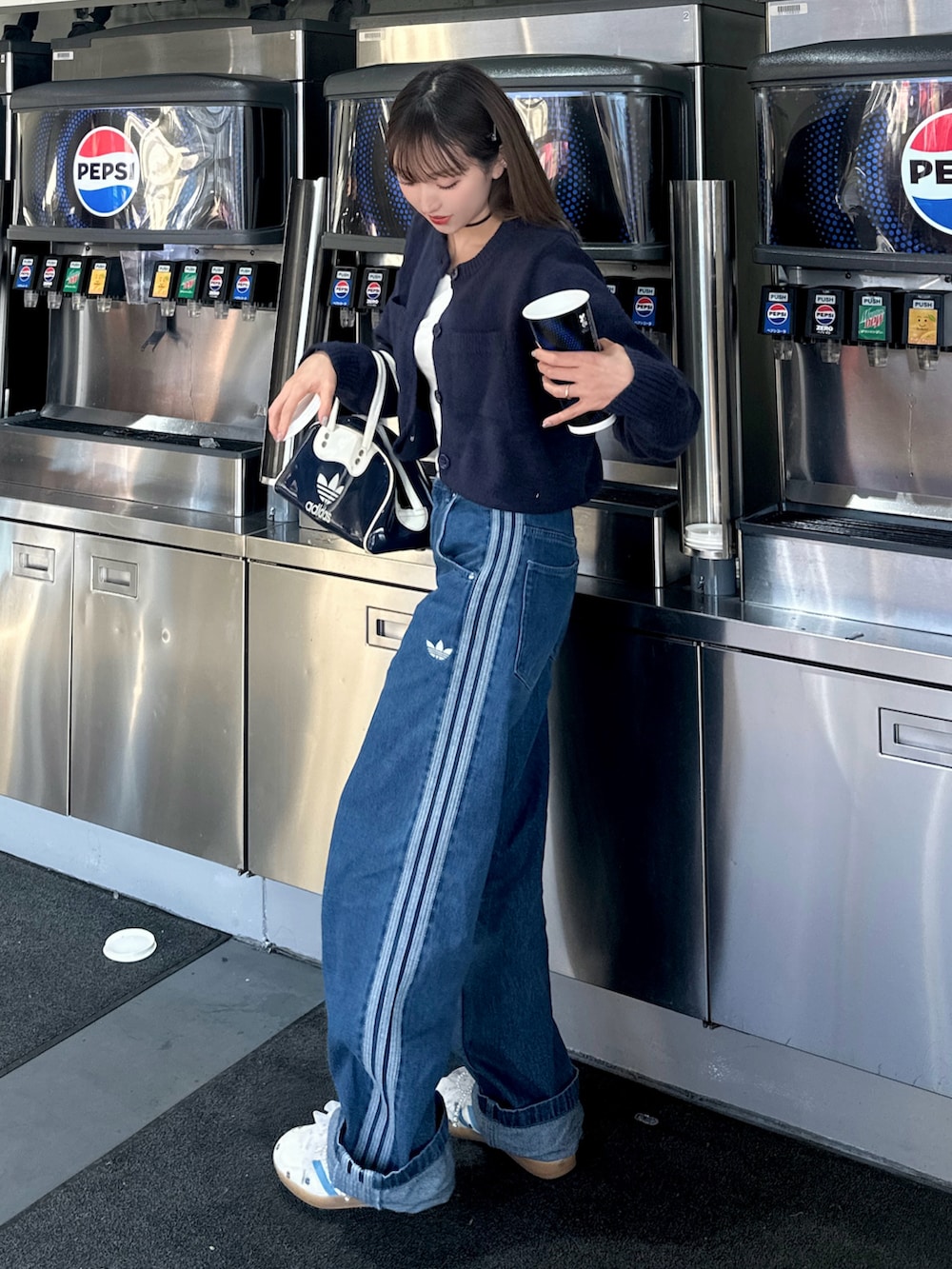 ブルー系のデニムパンツ、ホワイト系のスニーカー、ブルー系のカーディガン/ボレロを着用したレディースの秋コーディネートの2枚目の写真