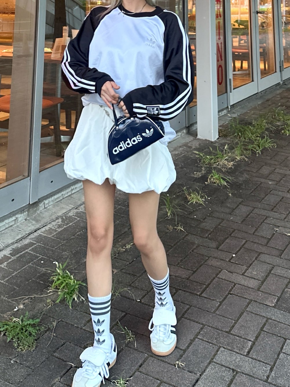 ホワイト系のTシャツ/カットソー、ホワイト系のスカート、ホワイト系のスニーカーを着用したレディースの春コーディネートの2枚目の写真