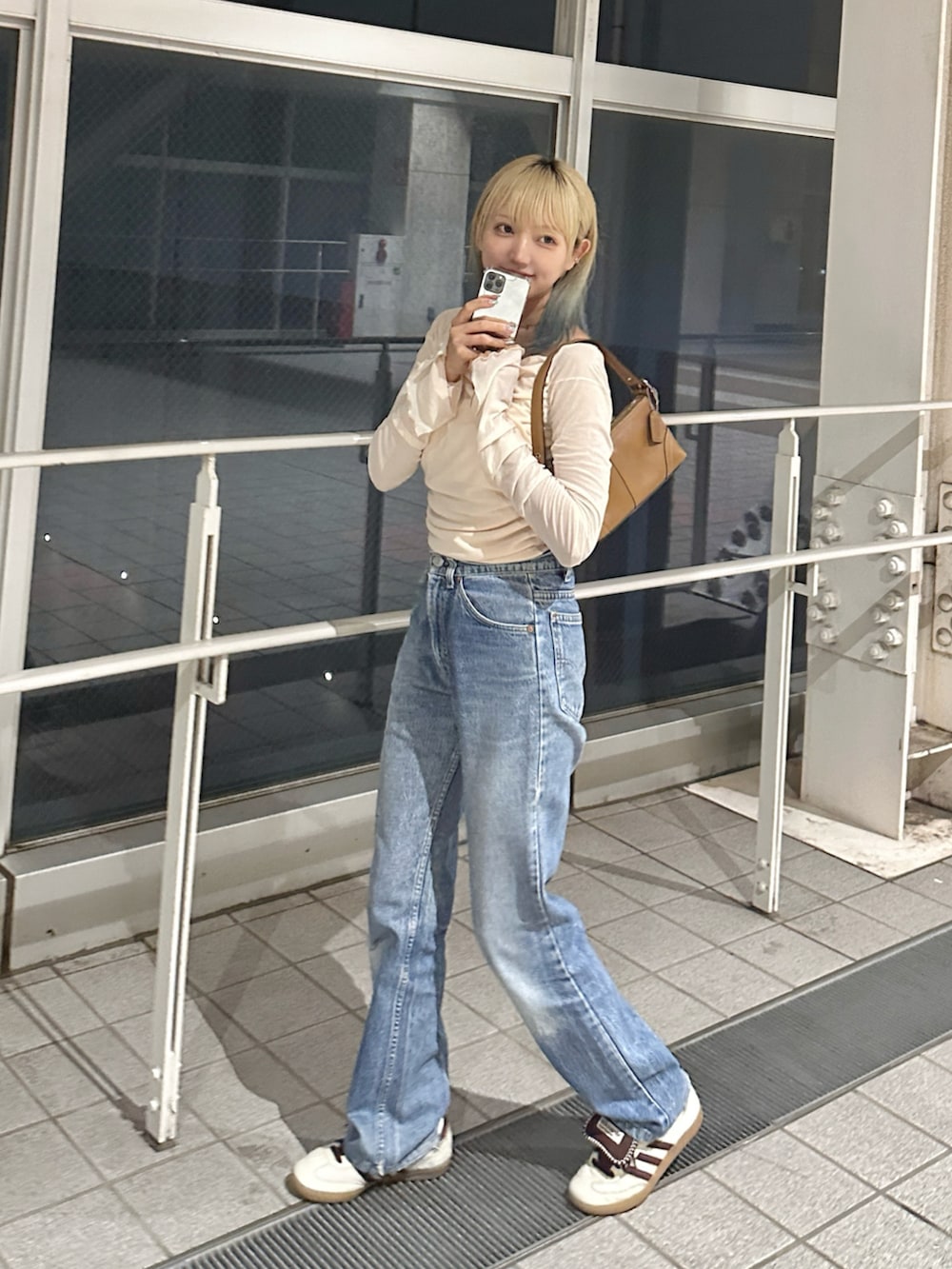 ブルー系のデニムパンツを着用したレディースの秋コーディネートの2枚目の写真