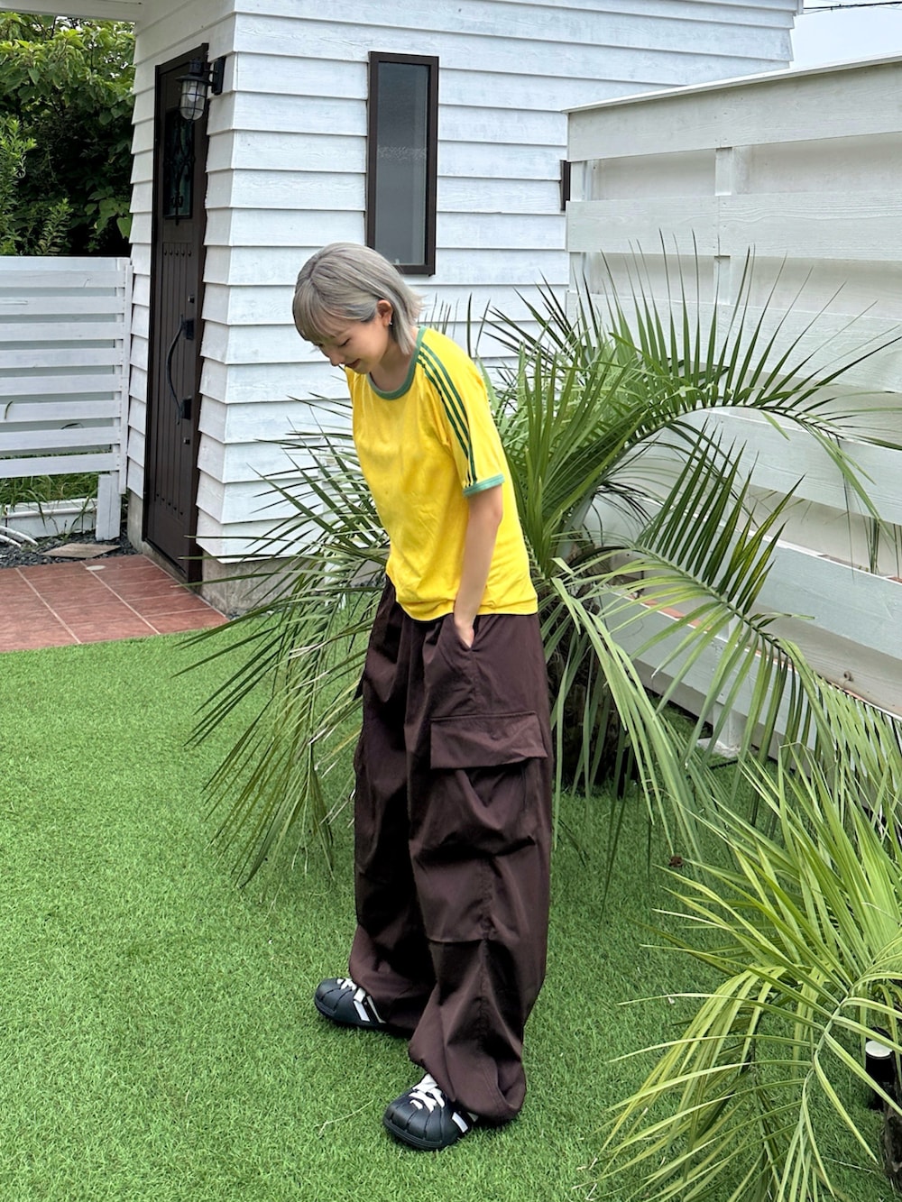 イエロー系のTシャツ/カットソー、ブラウン系のカーゴパンツ、ブラック系のサンダルを着用したレディースの夏コーディネートの2枚目の写真