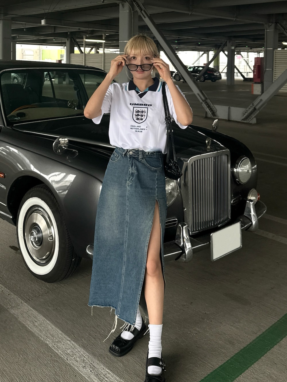 ホワイト系のトップス、ブルー系のデニムスカート、ブラック系のパンプスを着用したレディースの夏コーディネートの2枚目の写真