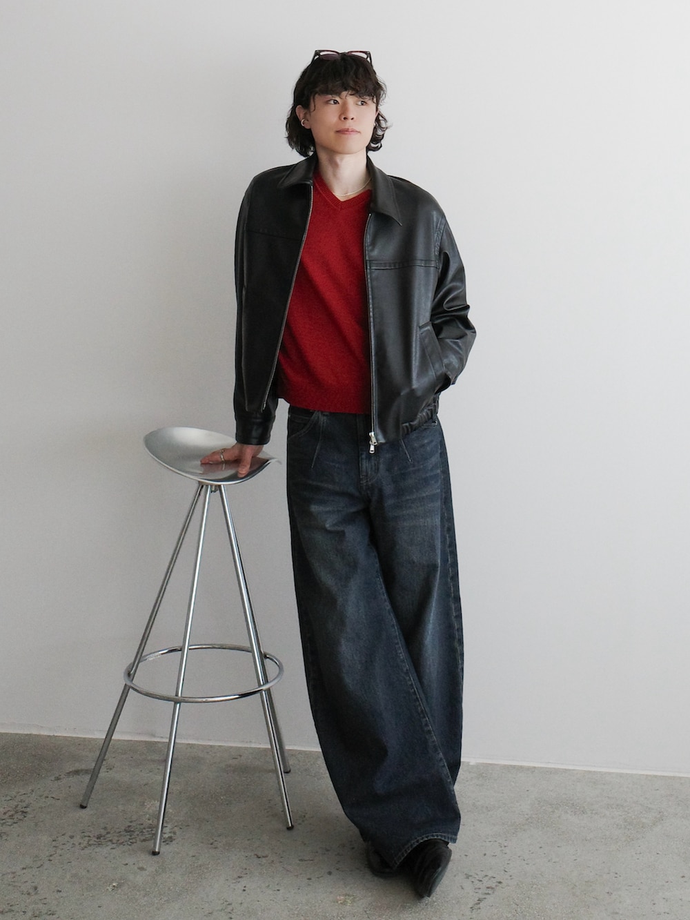 ブラック系のブルゾン、レッド系のニット/セーター、ブルー系のデニムパンツを着用したメンズの冬コーディネートの2枚目の写真