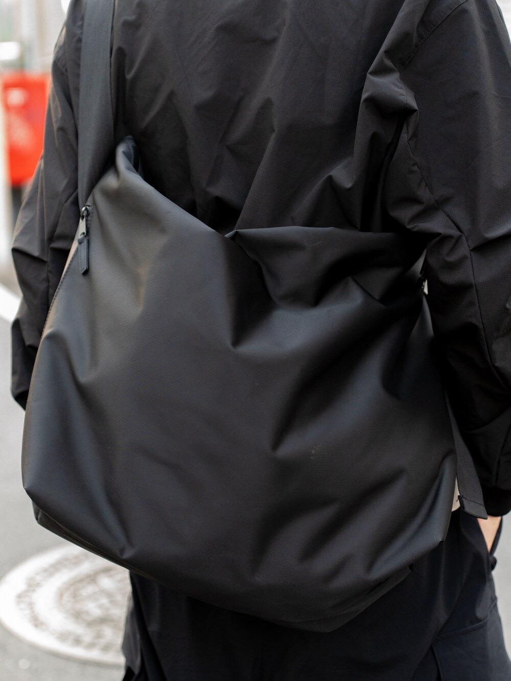 ブラック系のカーゴパンツ、ブラック系のメッセンジャーバッグ、ブラック系のTシャツ/カットソーを着用したメンズの春コーディネートの4枚目の写真