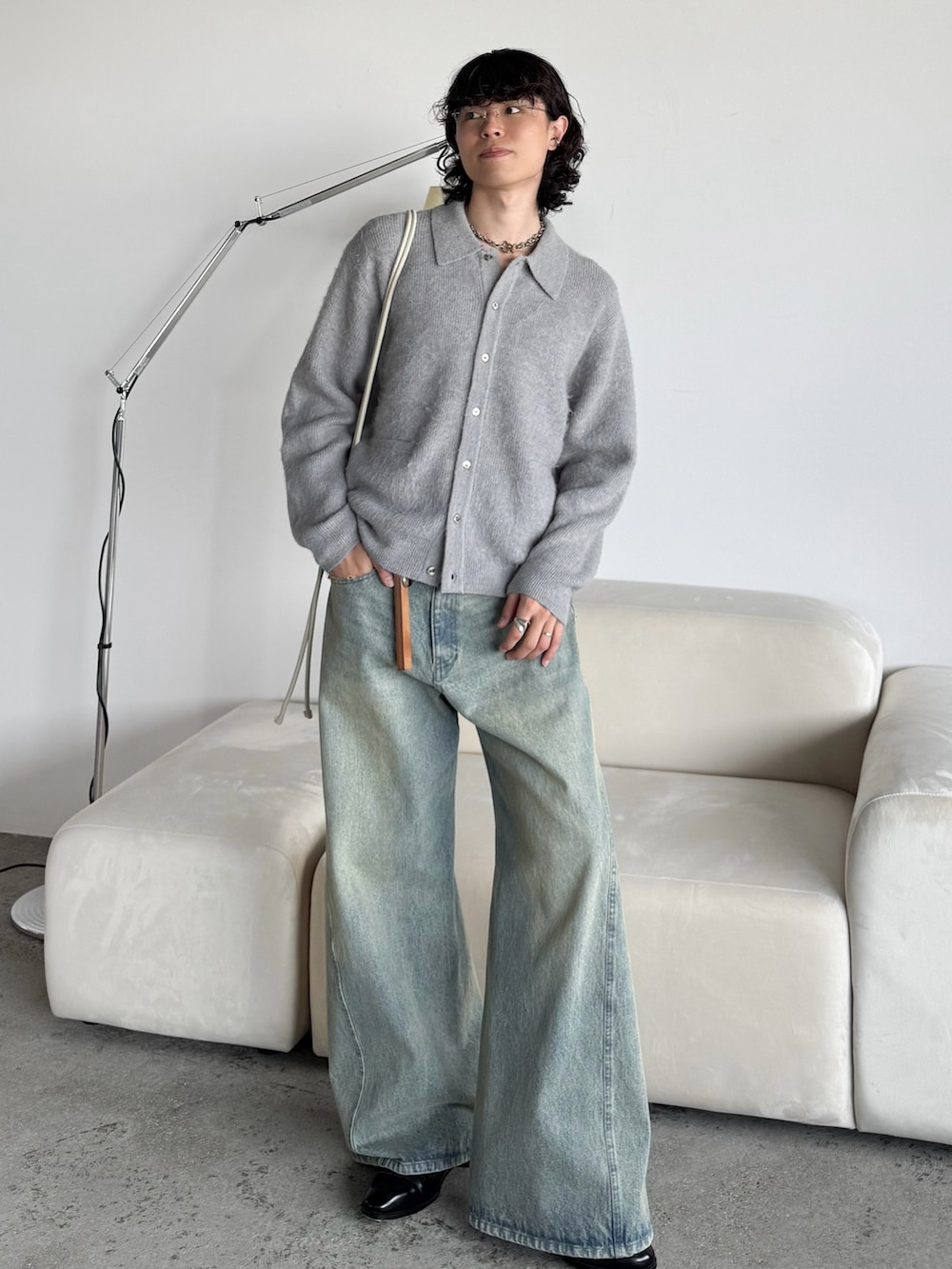 グレー系のニット/セーター、グレー系のショルダーバッグ、ブルー系のデニムパンツを着用したメンズの秋コーディネートの2枚目の写真