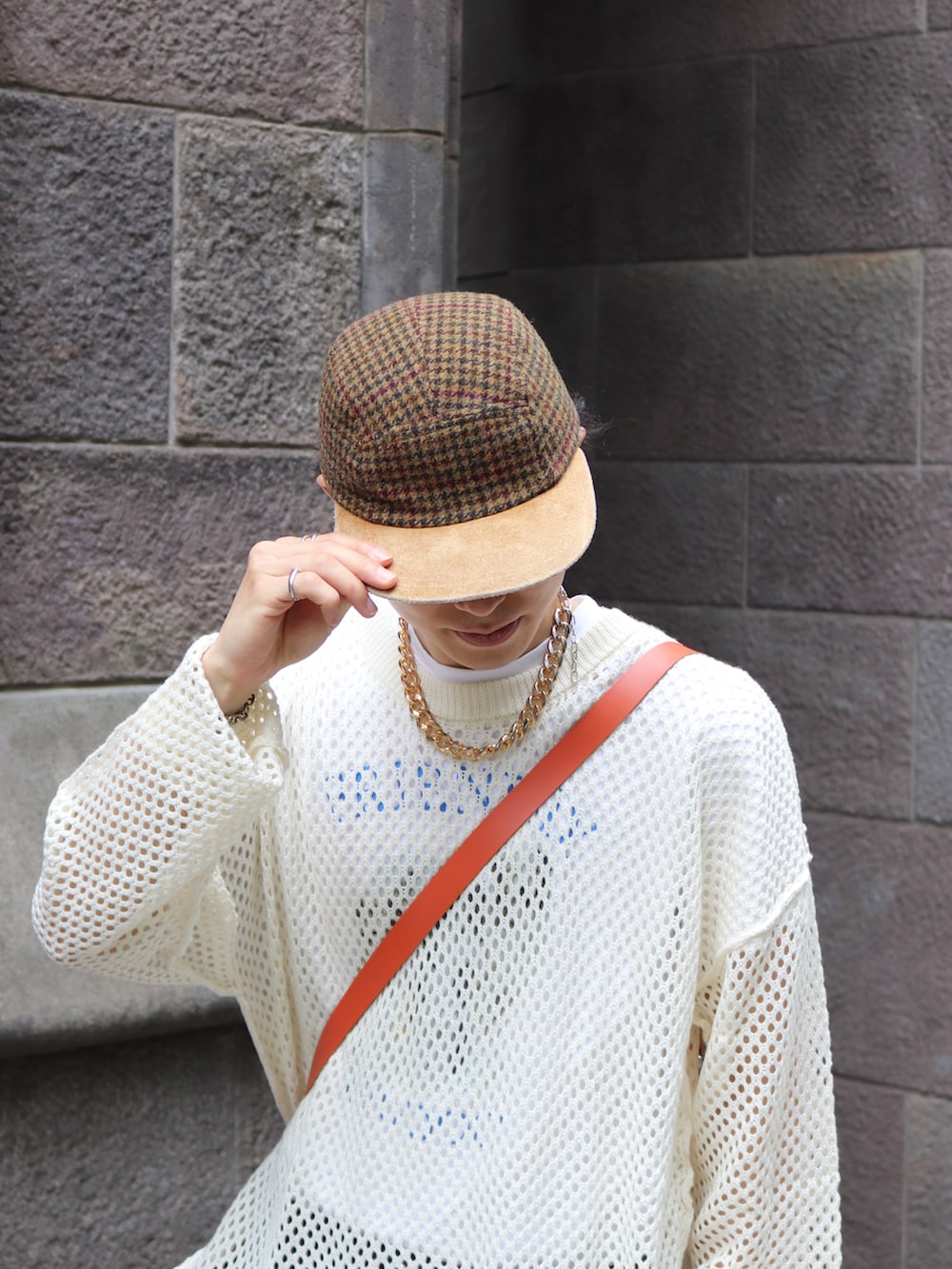 オレンジ系のショルダーバッグ、ホワイト系のニット/セーター、ブラック系のチノパンツを着用したメンズの夏コーディネートの5枚目の写真