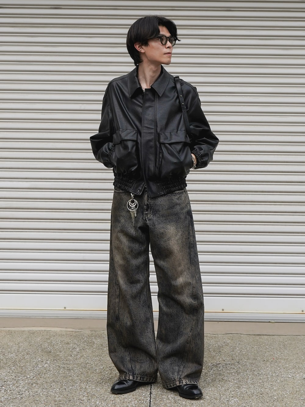 ブラック系のブルゾン、ブラック系のショルダーバッグ、ブルー系のデニムパンツを着用したメンズの秋コーディネートの2枚目の写真