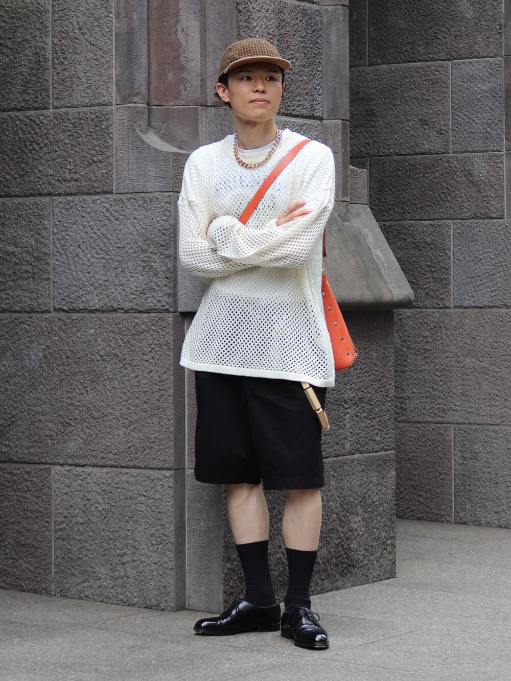 オレンジ系のショルダーバッグ、ホワイト系のニット/セーター、ブラック系のチノパンツを着用したメンズの夏コーディネートの3枚目の写真