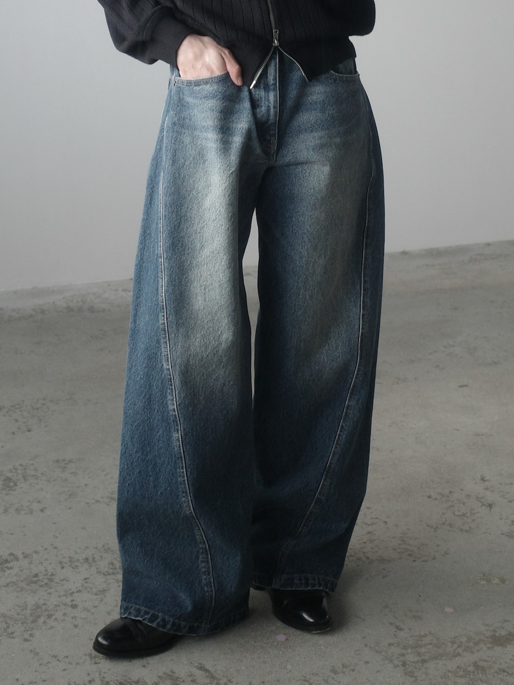 グレー系のブルゾン、ブラック系のショルダーバッグ、ブルー系のデニムパンツを着用したメンズの秋コーディネートの2枚目の写真