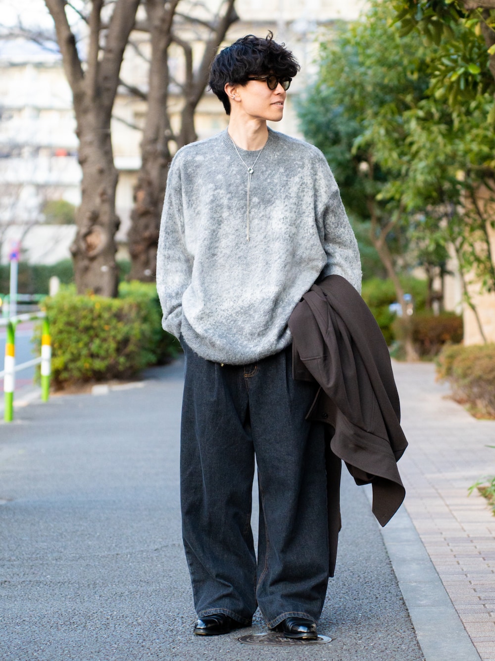 グレー系のニット/セーター、ブラウン系のトレンチコート、ブルー系のデニムパンツを着用したメンズの冬コーディネートの2枚目の写真