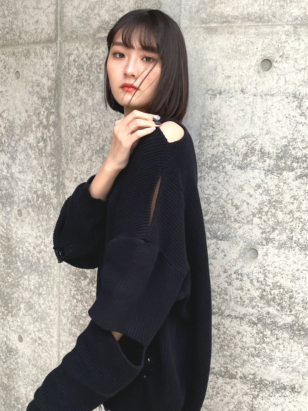 ブラック系のニット/セーター、ホワイト系のスカート、ブラック系のブーツを着用したレディースの春コーディネートの2枚目の写真