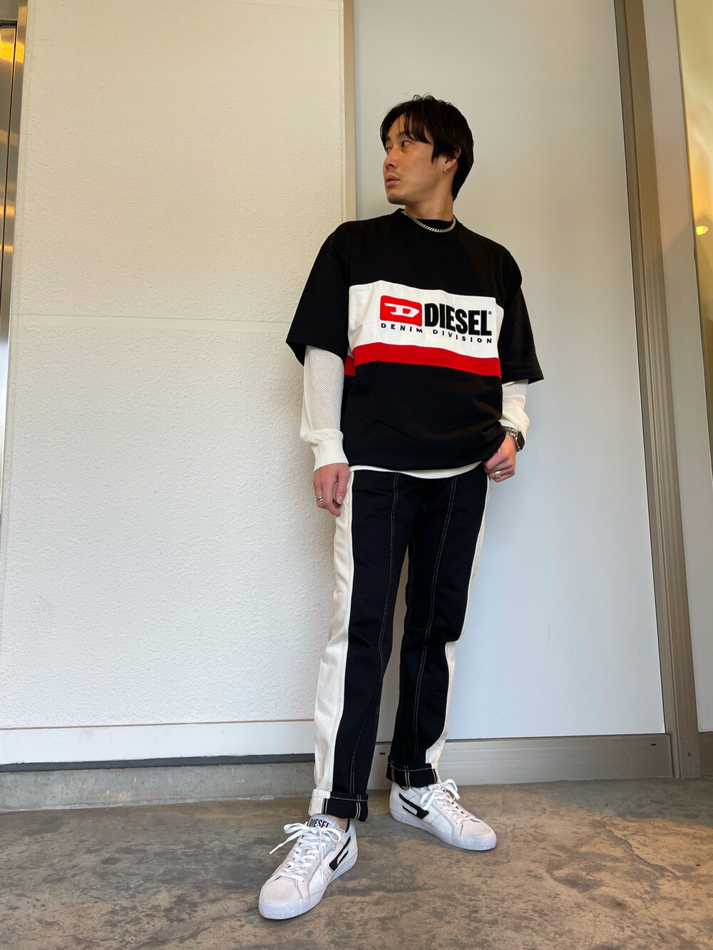 ブラック系のデニムパンツ、ブラック系のTシャツ/カットソー、ホワイト系のニット/セーターを着用したメンズの春コーディネートの2枚目の写真