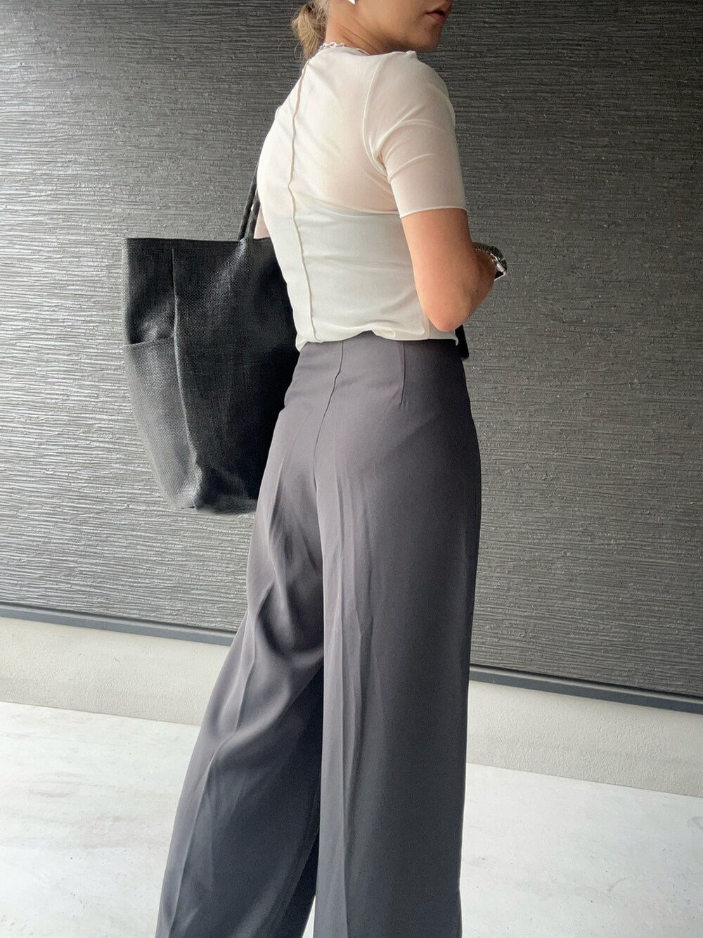 ブラック系のトートバッグ、グレー系のスラックス、ホワイト系のトップスを着用したレディースの夏コーディネートの4枚目の写真