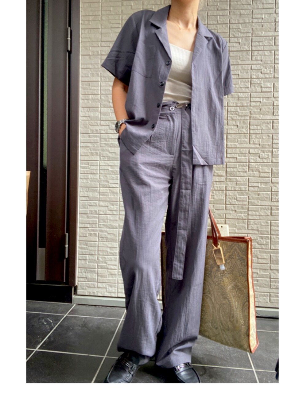 グレー系のパンツドレス、ブラック系のローファー、シルバー系のアナログ腕時計を着用したレディースの夏コーディネートの2枚目の写真