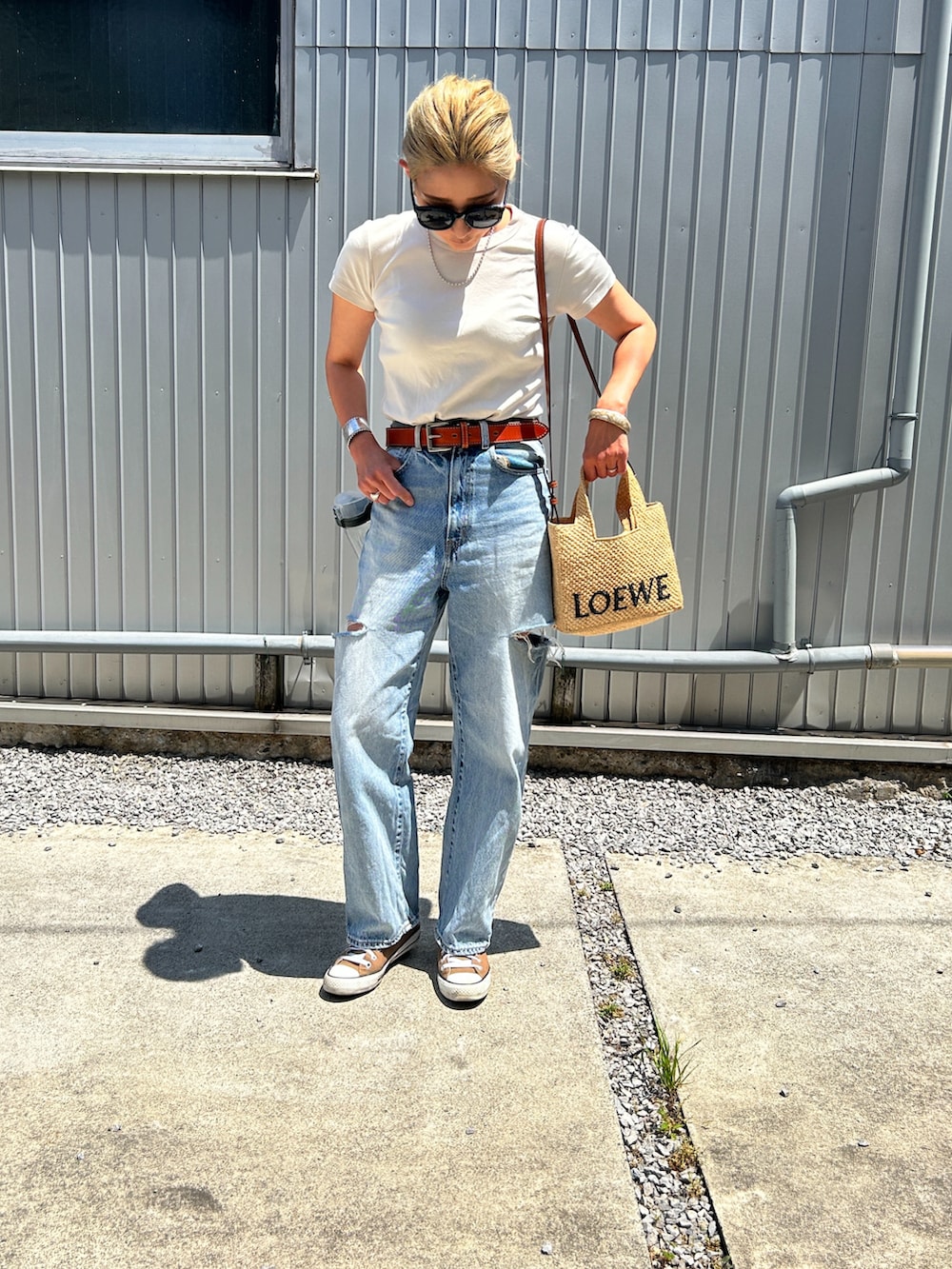 ホワイト系のTシャツ/カットソー、ブルー系のデニムパンツ、ベージュ系のかごバッグを着用したレディースの春コーディネートの3枚目の写真