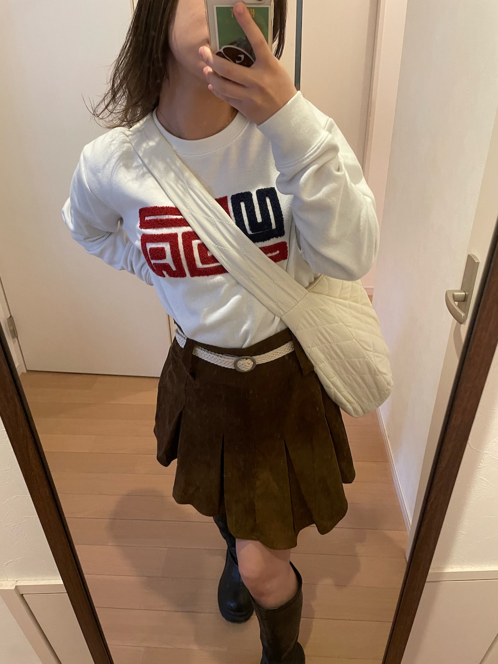 ブラウン系のスカート、ホワイト系のバッグ、ブラウン系のカバーオールを着用したレディースの春コーディネートの2枚目の写真