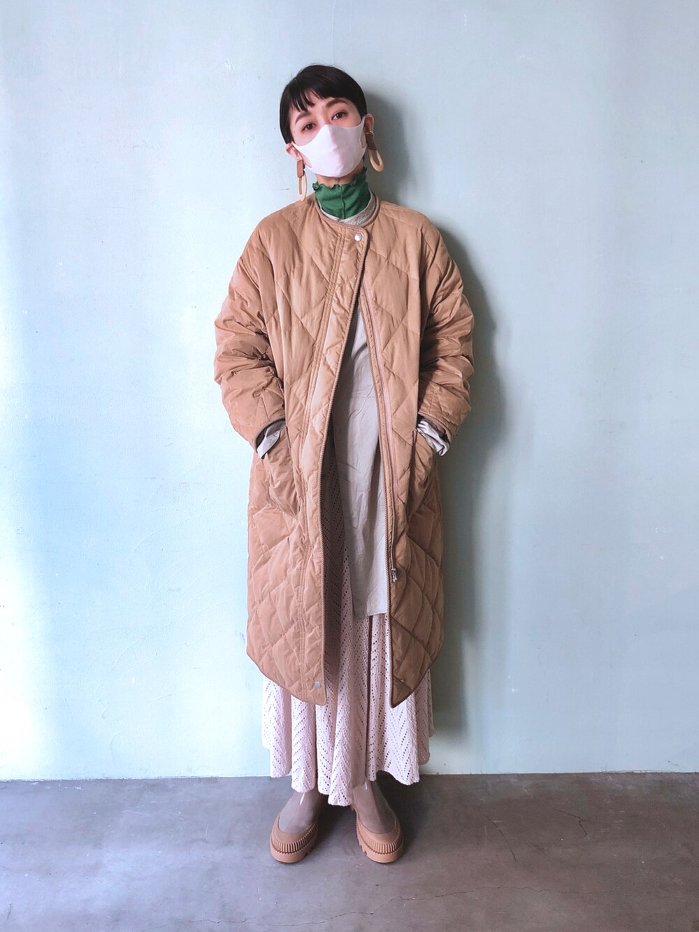 グレー系のレインシューズ、ホワイト系のスカート、グリーン系のシャツ/ブラウスを着用したレディースの冬コーディネートの2枚目の写真