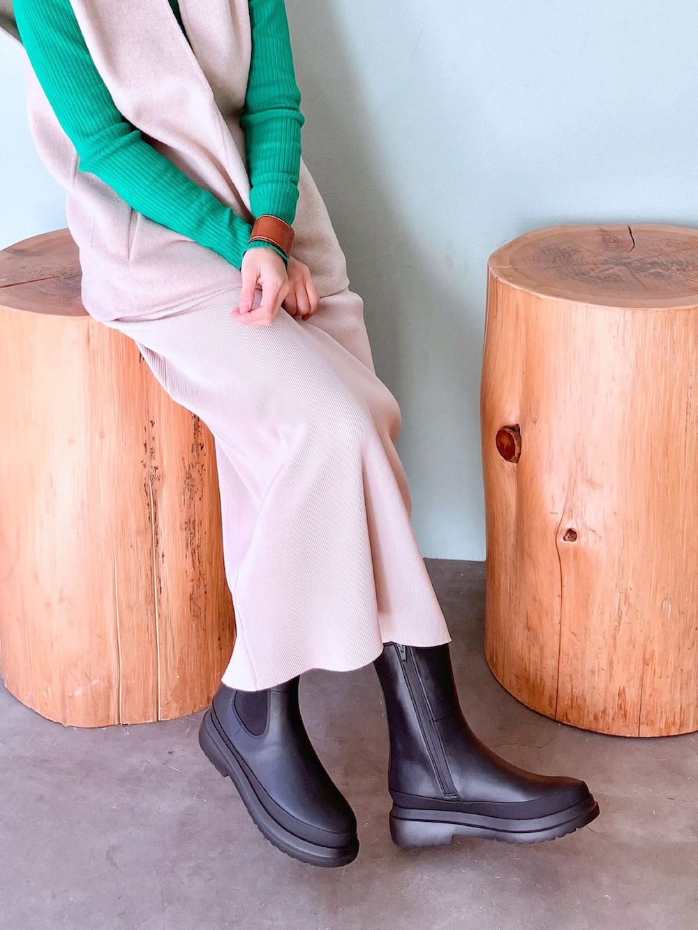 ブラック系のブーツ、ホワイト系のスカート、ベージュ系のベストを着用したレディースの春コーディネートの2枚目の写真