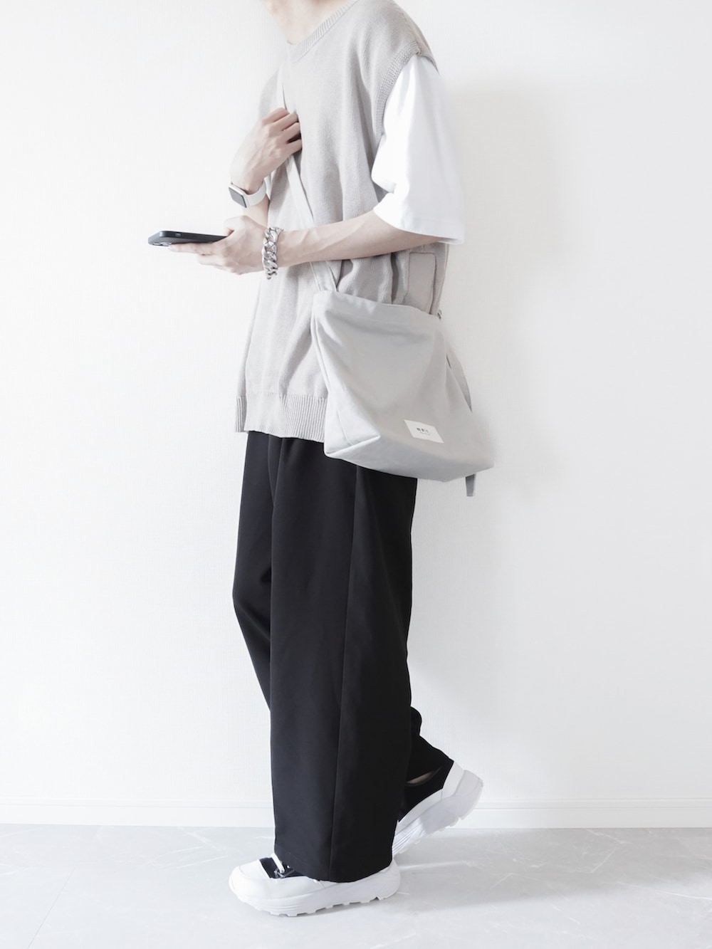 ベージュ系のベスト、ホワイト系のTシャツ/カットソー、ブラック系のスラックスを着用したメンズの春コーディネートの3枚目の写真