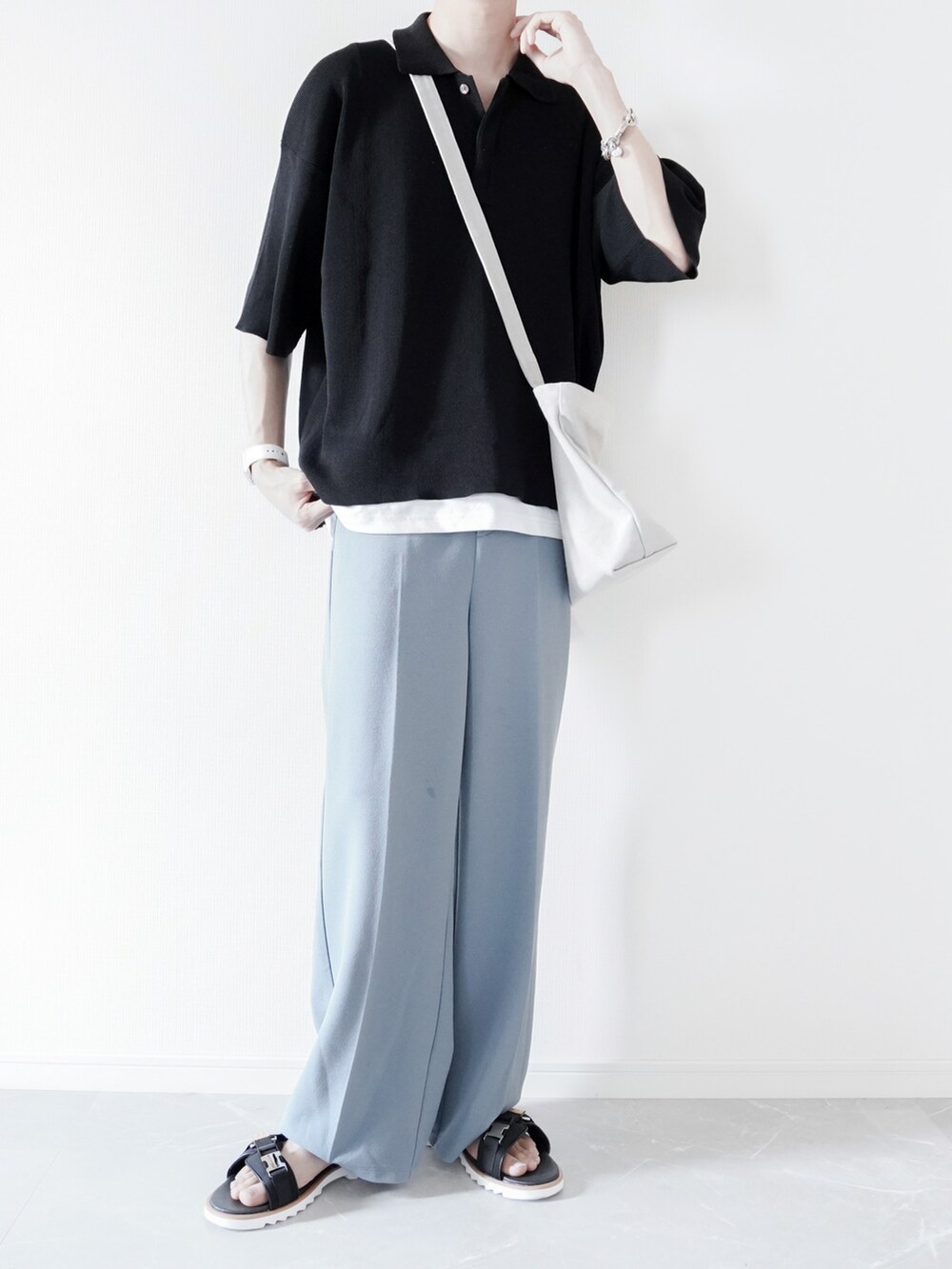 ブラック系のポロシャツ、ホワイト系のタンクトップ、ブルー系のスラックスを着用したメンズの春コーディネートの2枚目の写真