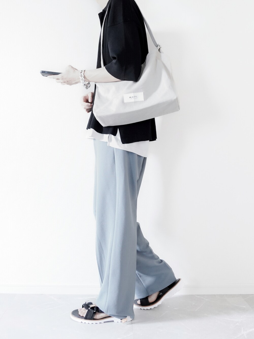 ブラック系のポロシャツ、ホワイト系のタンクトップ、ブルー系のスラックスを着用したメンズの春コーディネートの4枚目の写真